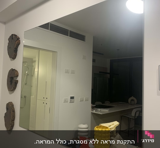 מראה גדולה על קיר עם חפצים על שולחן